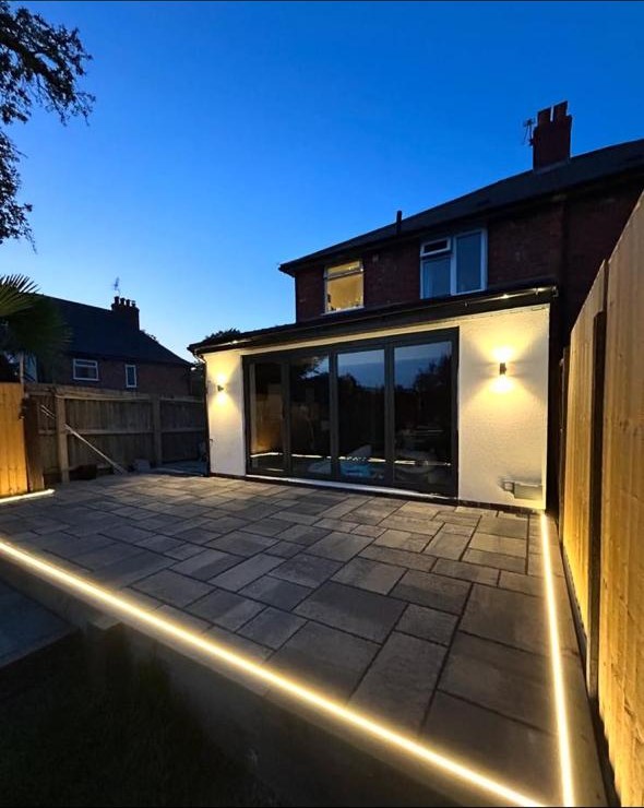 Completed rear extension and illuminated paved patio at dusk