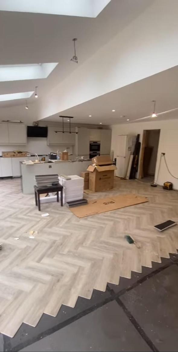 Open-plan kitchen during final floor and cabinet fit-out